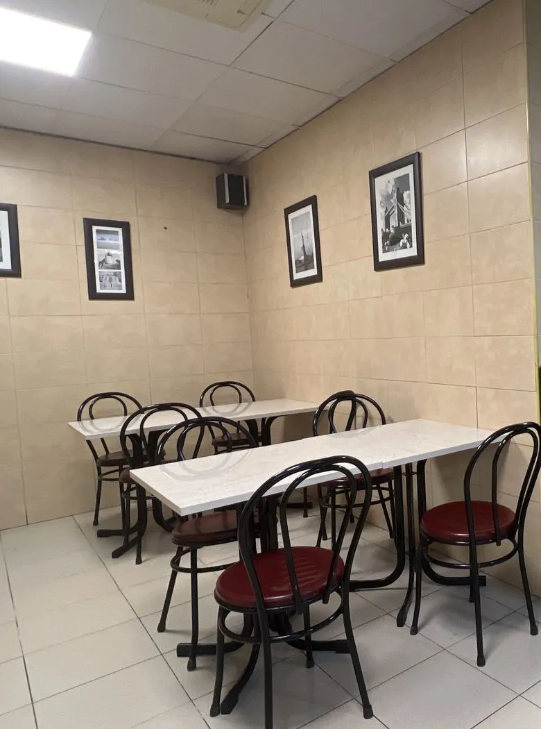 Mesas de mármol con sillas negras de asiento rojo y cuadros enmarcados en la pared